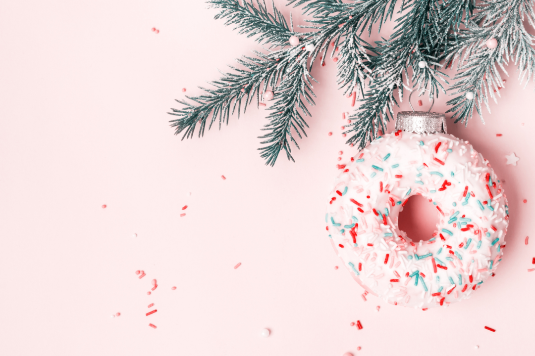 sprinkle donut ornament hanging on a christmas tree branch