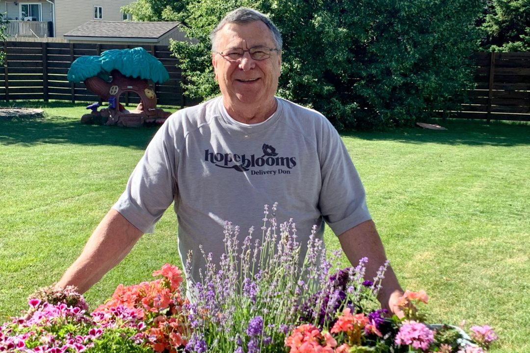 Don Krenzel_male volunteer standing in front of flowers