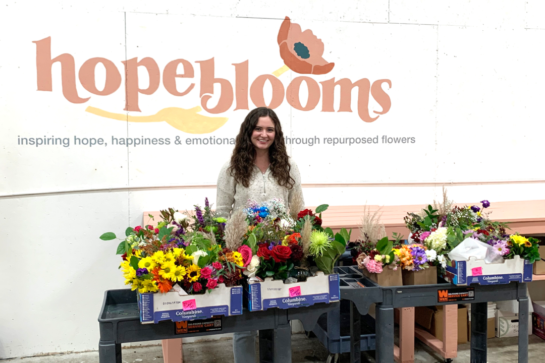 Ellia Dalzell stands behind bouquets of flowers on carts
