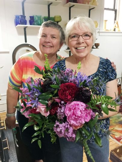 Laurie Krenzel & Carlotta Broeckel_two women standing together and smiling holding a bouquet of flowers