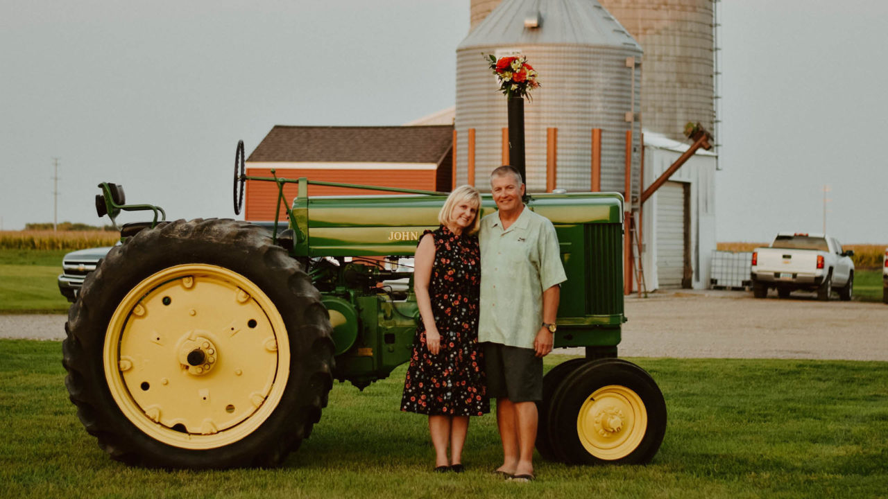 Sharon & Steve Miller_couple stands in front of John Deere tractor
