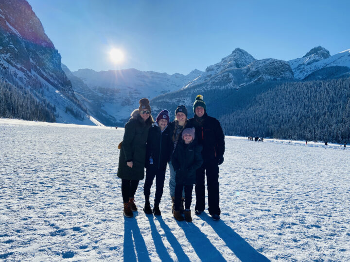 Zenker family of 5 standing in front in winter clothes with snow and mountains in background